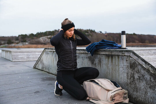 Young woman in sport clothes, kneeling next to her backpack