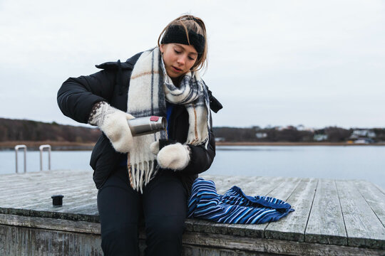 Young woman having a coffee brake in the dock in a cold day