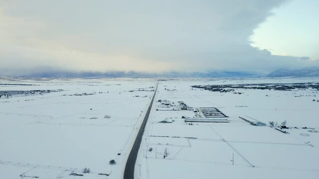 Two lane road disappears in toward distant horizon through snowy fields
