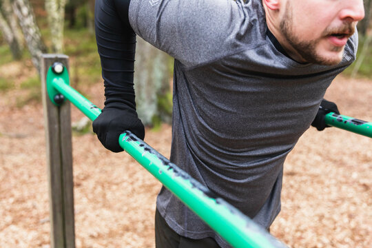 Unrecognizable sporty man doing dips in an outdoors gym