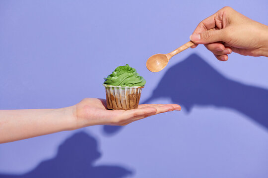 Hand holding a spoon scooping matcha cupcake