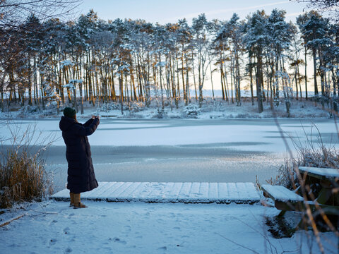 woman taking a picture in winter landscape