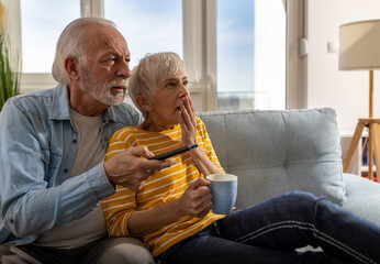 Mature couple watching scary movie at home