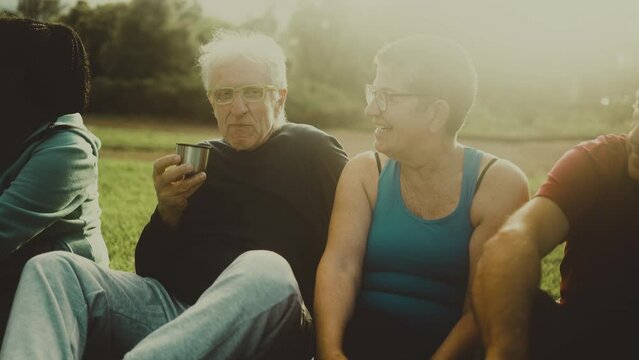 Happy multiracial senior friends drinking a tea after workout session in a park