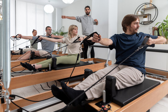 Group doing tendon stretch on Pilates reformers