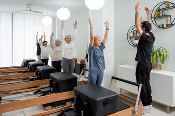 Senior women exercising with trainer in pilates studio
