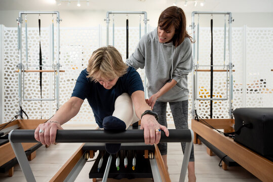 Woman doing split during Pilates training with trainer