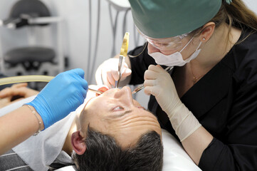 adult man praying with his eyes looks at the doctor who tears his tooth dentistry hurts the request of man woman pull a tooth out