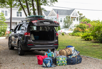 Packing luggage in pile next to car for family road trip 