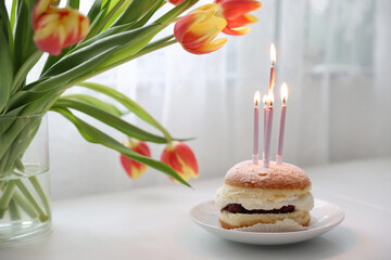 Delicious birthday cake with candles on white table next to tulip flowers birthday cake alternative...