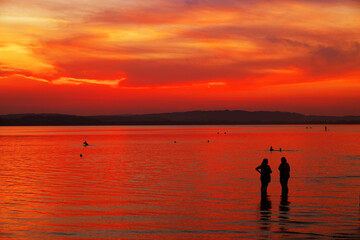 Naklejka na ściany i meble Tourists enjoying the sunset at Sempach lake in Switzerland, Europe