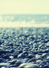 Obraz premium Marine background. Pebble beach on a sunny day. Pebbles close-up, sea and sky in summer without people, soft selective focus 