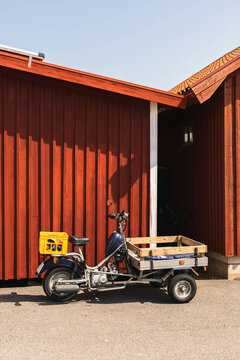 Flatbed moped behind small boat houses