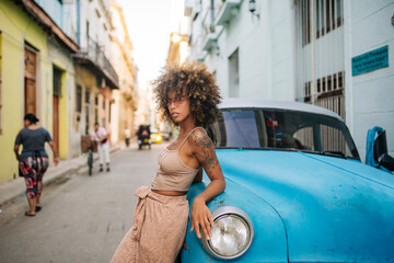 Confident Cuban female leaning on blue car