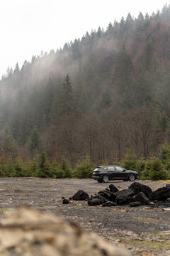 Car standing in winter foggy forest.Mountains background