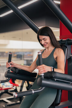 Cheerful sportswoman doing abs exercise in gym