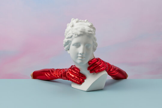 Aphrodite bust with hands in red gauntlets.