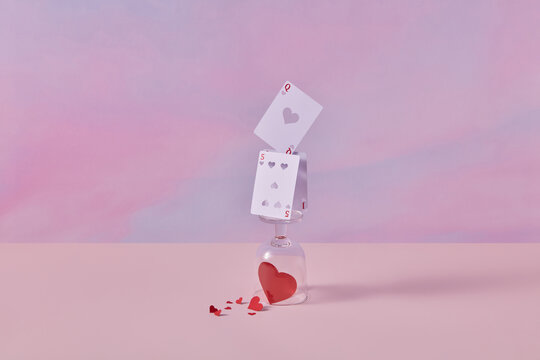 Cards on wineglass with red paper hearts inside.