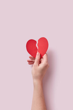 Red ripped paper cut heart held by female hand.