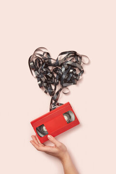 Black tape like heart of red cassette in female hand.
