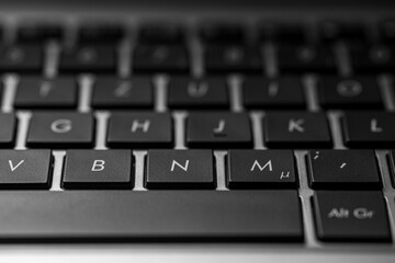 closeup of a laptop keyboard with black keys and a silver case.
