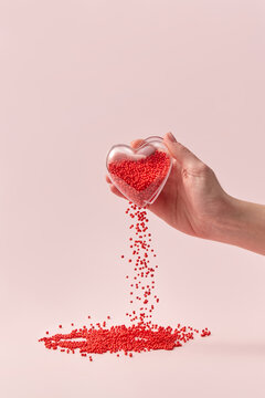 Glass heart in hand with red balls falling out.