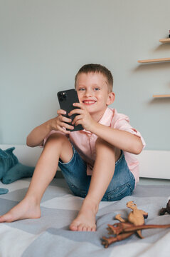 Happy boy browsing cellphone on bed