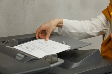 Crop anonymous woman using printer in office

