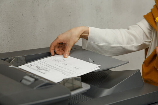 Crop anonymous woman using printer in office
