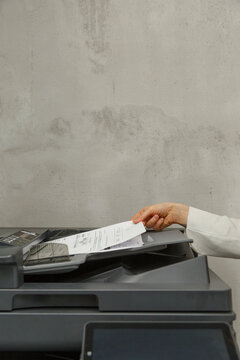 Crop faceless female assistant printing documents
