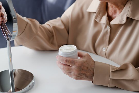 Hands of senior woman holding a jar of face cream