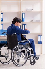 Young male employee in wheelchair working in the office