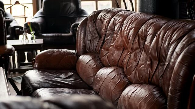 old leather vintage sofa stands in front of table in old interior. Leather retro sofa with squished seats in expensive office or home interior.