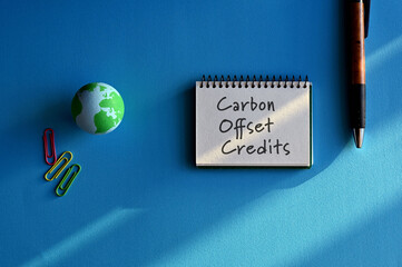 There is a notebook with the word Carbon Offset Credits. It is eye-catching image.