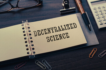 There is a notebook with the word Decentralized Science. It is eye-catching image.