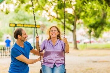 50-59 years senior happiness relationship. Hispanic family enjoy life couple with a swing in a park