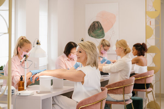 Professional manicurists giving manicure to clients