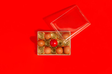 Easter concept with packed eggs in a chocolate candy box. Creative holiday idea with red egg on red background. Flat lay.