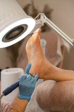 Crop pedicurist polishing heel with machine