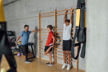 Group of young man teenagers relaxing stretching and having a break on the wooden gymnastics wall...