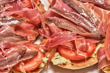 Delicious toasts with Iberian ham, sliced tomatoes, avocado and a touch of virgin olive oil, a perfect combination of flavors and textures.