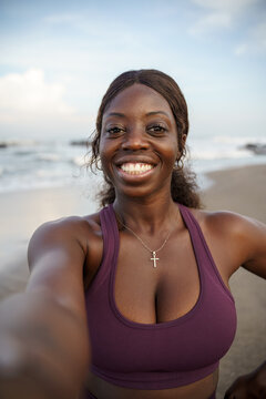 Smiling woman in sportswear taking selfie at the beach