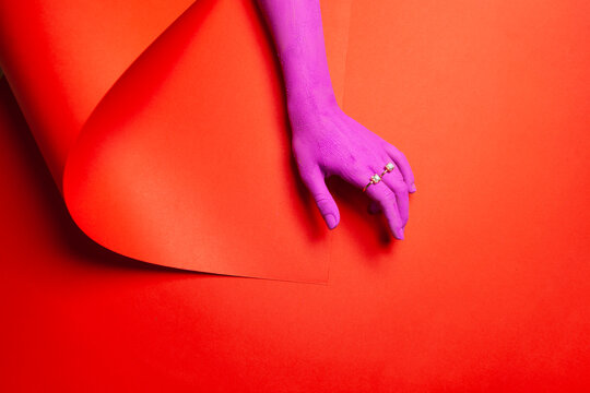 Purple painted hand on a red background