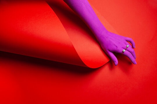 Purple painted hand on a red background