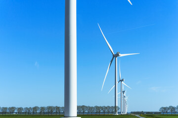 Row of wind turbines, blue sky background. Banner with many wind turbines. Green energy, eco-friendly electricity, renewable resources.