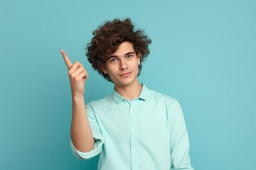 Jovem bonito e charmoso mostrando algo com o dedo indicador, lugar para texto, anúncio, copie o espaço. isolado no fundo azul. direção. linguagem corporal. venda, loja