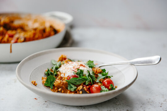 A dish of pearl couscous with tomatoes and aubergine.