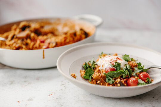 A dish of pearl couscous with tomatoes and aubergine.