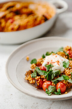 A dish of pearl couscous with tomatoes and aubergine.