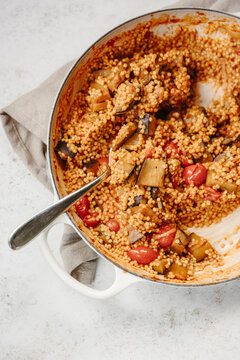 A dish of pearl couscous with tomatoes and aubergine.